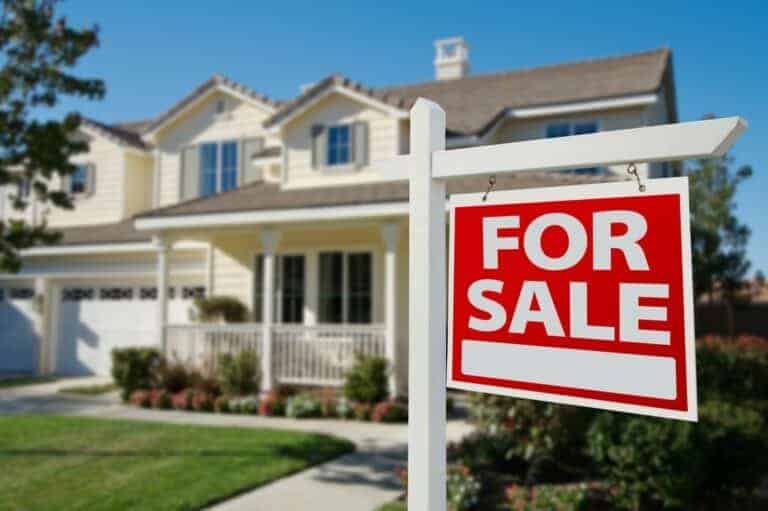 white house with a for sale sign in front of it