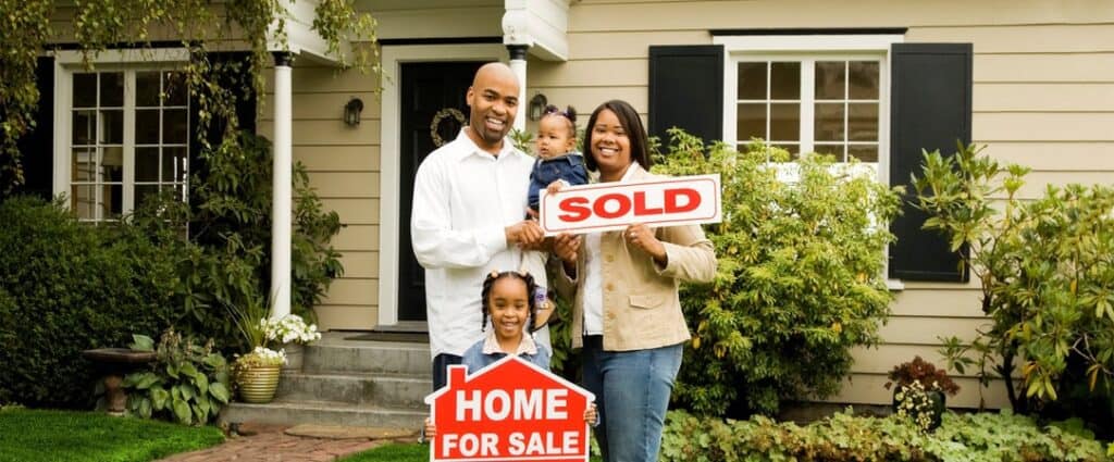 Family standing in front of a home with a sold sign