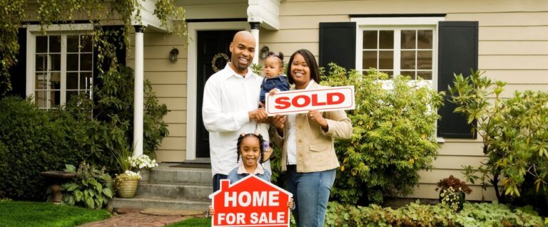 Family standing in front of a home with a sold sign