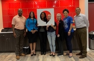 group of adults posing for a picture. two in the middle are holding up a cut out comment bubble sign